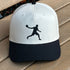 White and black baseball cap with a black silhouette of a player on a wooden surface